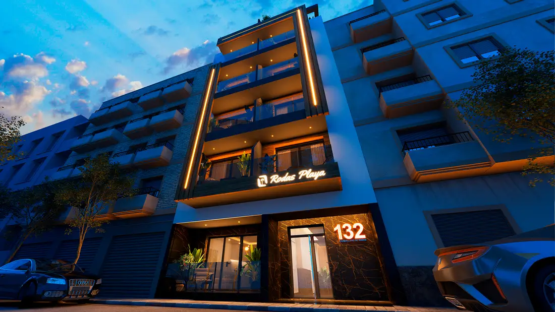 Rodas Playa at dusk, seen along Calle Caballero de Rodas — the lit timber-slat frame, the illuminated name over the entrance and the number 132